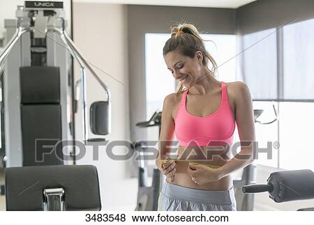 Woman in fitness center measuring her waist View Large Photo Image Stock Photo - Woman in fitness center measuring her waist. Fotosearch