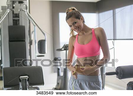 Woman in fitness center measuring her waist View Large Photo Image Stock Photo - Woman in fitness center measuring her waist. Fotosearch