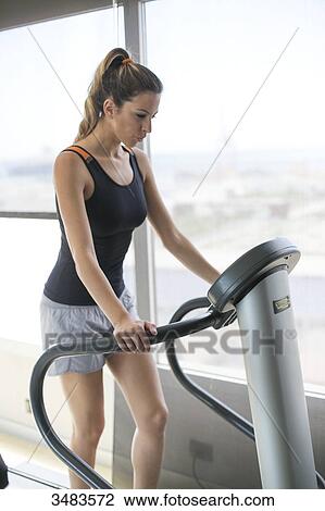 Stock Image - Woman running on treadmill in fitness center. Fotosearch