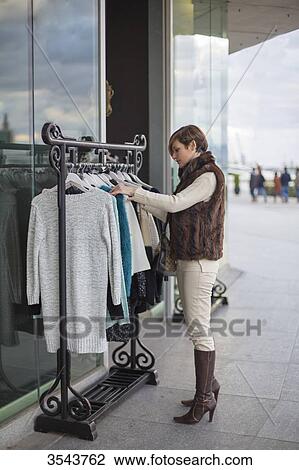 Woman searching fot clothes in a store outside View Large Photo Image Stock Image - Woman searching fot clothes in a store outside. Fotosearch