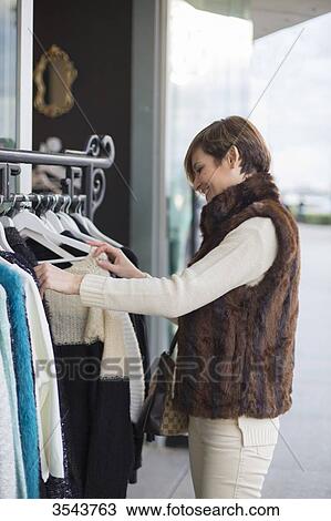Woman searching fot clothes in a store outside View Large Photo Image Stock Image - Woman searching fot clothes in a store outside. Fotosearch