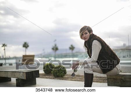 Woman sitting on a bench in citycenter close to the harbour View Large Photo Image Stock Photo - Woman sitting on a bench in citycenter close to the harbour. Fotosearch