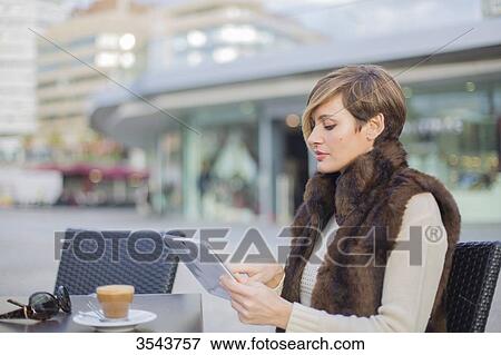 Woman with tablet in a Cafe outdoors View Large Photo Image Stock Photo - Woman with tablet in a Cafe outdoors. Fotosearch