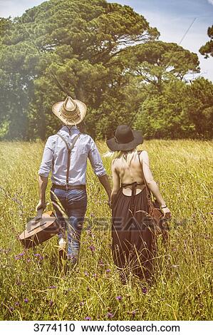 Stock Image - Young couple Hipster ride in the country, holding in one hand a guitar the other. Fotosearch