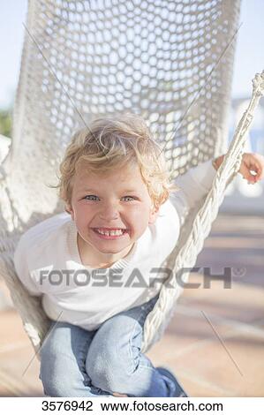 Young funny boy smiling at camera in a hammock View Large Photo Image Stock Image - Young funny boy smiling at camera in a hammock. Fotosearch
