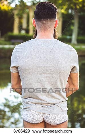 Stock Photo - Young Hipster standing back, in his underwear, before nature. Fotosearch