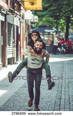 Young man carrying his girlfriend on his back in an urban environment View Large Photo Image Stock Photo - Young man carrying his girlfriend on his back in an urban environment. Fotosearch