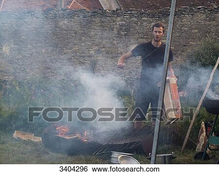 Young man preparing a fire to grill meat View Large Photo Image Stock Photograph - Young man preparing a fire to grill meat. Fotosearch