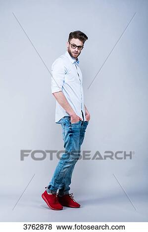 Young man standing in shirt, side, hands in pockets, eyes on the side View Large Photo Image Stock Photo - Young man standing in shirt, side, hands in pockets, eyes on the side. Fotosearch