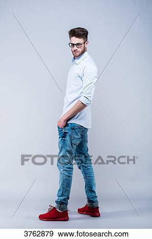 Young man standing in shirt, side, hands in pockets, looking toward the lens View Large Photo Image Stock Photo - Young man standing in shirt, side, hands in pockets, looking toward the lens. Fotosearch