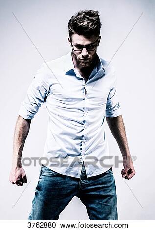 Young man standing in white shirt, face, clenched fists View Large Photo Image Stock Image - Young man standing in white shirt, face, clenched fists. Fotosearch