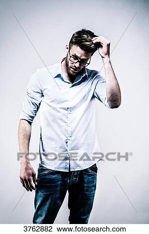 Young man standing in white shirt, face, hand in hair View Large Photo Image Stock Image - Young man standing in white shirt, face, hand in hair. Fotosearch