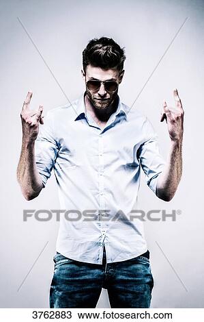 Young man standing in white shirt, face, hands in the air, making the symbolic retorts hands View Large Photo Image Stock Image - Young man standing in white shirt, face, hands in the air, making the symbolic retorts hands. Fotosearch