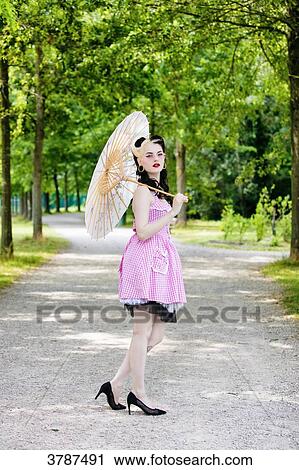 Stock Image - Young Pin Up profile, an umbrella in hand, looking at the camera. Fotosearch