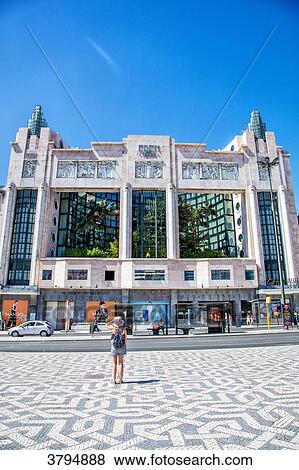 Stock Photo - Young woman from behind, look at the building Eden Teatro, instead of restaurants, Lisbon, Portugal. Fotosearch