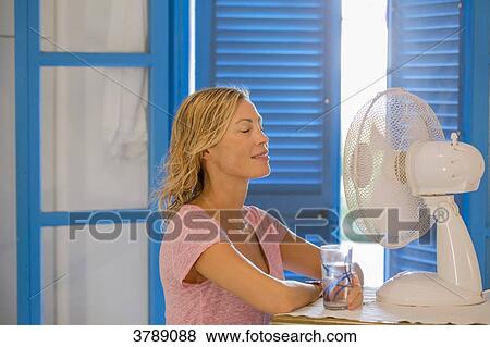 Young woman in profile in front a fan with a glass of water. View Large Photo Image Stock Photo - Young woman in profile in front a fan with a glass of water.. Fotosearch