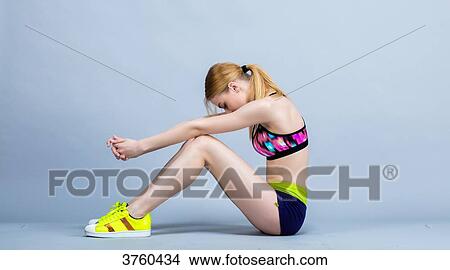 Young woman sitting in keeping fitness, profile, focused, head down View Large Photo Image Picture - Young woman sitting in keeping fitness, profile, focused, head down. Fotosearch