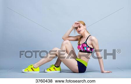Stock Photo - Young woman sitting in keeping fitness, Profile, takes a breath. Fotosearch