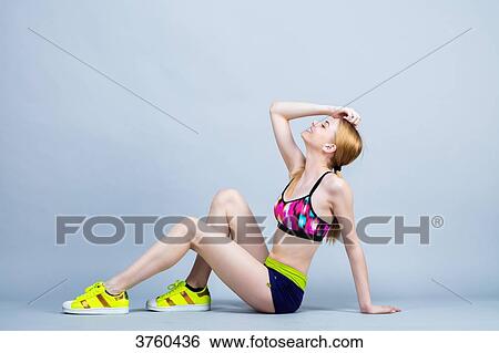 Young woman sitting, smiling, dressed in fitness, head back View Large Photo Image Stock Photograph - Young woman sitting, smiling, dressed in fitness, head back. Fotosearch