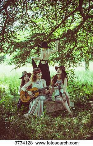 Youth group Hipster sitting on a rock, listening and playing the guitar View Large Photo Image Stock Photo - Youth group Hipster sitting on a rock, listening and playing the guitar. Fotosearch