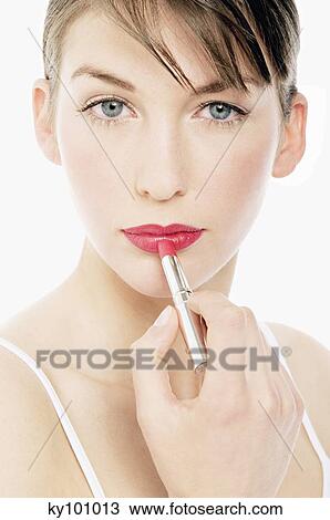 Stock Image - Young Woman face making-up with a lipstick, close-up (studio). Fotosearch