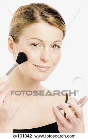 Stock Image - Young Woman face making-up with a brush, close-up (studio). Fotosearch