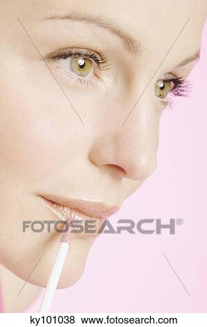 Stock Photo - Young Woman face making-up with a lipstick, close-up (studio). Fotosearch