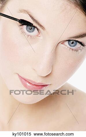 Stock Photography - Young Woman face making-up with mascara, close-up (studio). Fotosearch