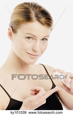 Stock Photo - Young Woman face with cream on her finger (studio). Fotosearch