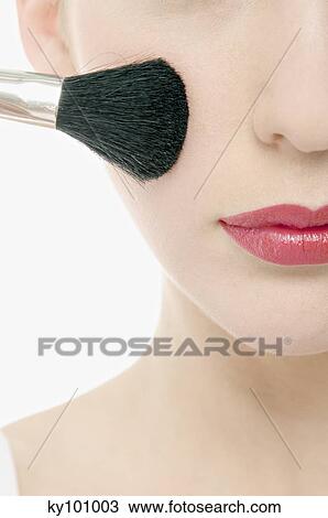 Young Woman face with Make-Up, holding a brush in front of her, close-up (studio) View Large Photo Image Stock Image - Young Woman face with Make-Up, holding a brush in front of her, close-up (studio). Fotosearch