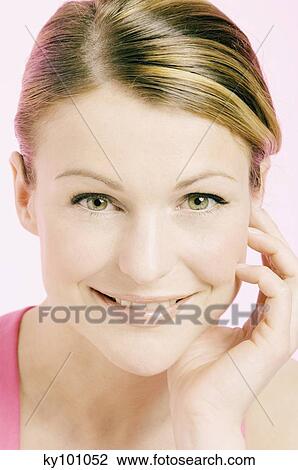 Young Woman face with make up, looking at the camera, smiling, hand on her cheek, close-up (studio) View Large Photo Image Stock Image - Young Woman face with make up, looking at the camera, smiling, hand on her cheek, close-up (studio). Fotosearch