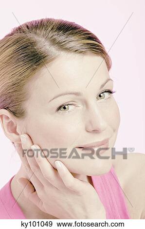 Young Woman face with make up, looking at the camera, smiling, hand on her cheek, close-up (studio) View Large Photo Image Stock Photo - Young Woman face with make up, looking at the camera, smiling, hand on her cheek, close-up (studio). Fotosearch