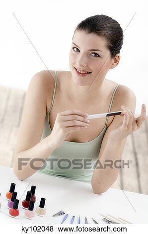 Stock Photo - Woman filing her nails, inside. Fotosearch