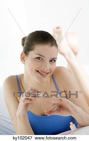 Stock Photo - Woman painting her fingernails, inside. Fotosearch