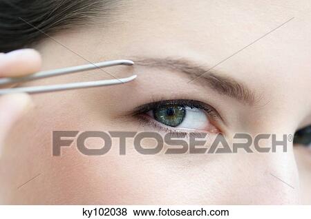 Woman plucking her eyebrow, close up (studio) View Large Photo Image Stock Photo - Woman plucking her eyebrow, close up (studio). Fotosearch