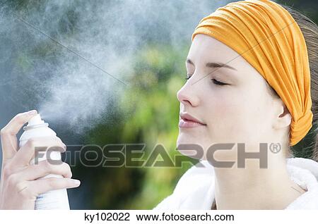 Woman spraying water on her face, inside View Large Photo Image Stock Image - Woman spraying water on her face, inside. Fotosearch