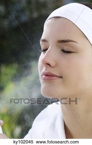 Woman spraying water on her face, inside View Large Photo Image Stock Photography - Woman spraying water on her face, inside. Fotosearch