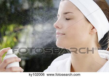Woman spraying water on her face, interior View Large Photo Image Stock Photograph - Woman spraying water on her face, interior. Fotosearch