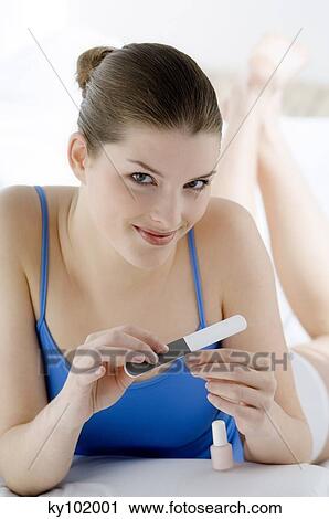 Young Woman smiling, filing her nails, interior View Large Photo Image Stock Image - Young Woman smiling, filing her nails, interior. Fotosearch
