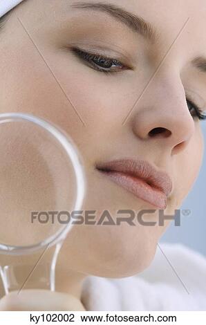 Stock Image - Young Woman with a magnifying glass, close-up (studio). Fotosearch