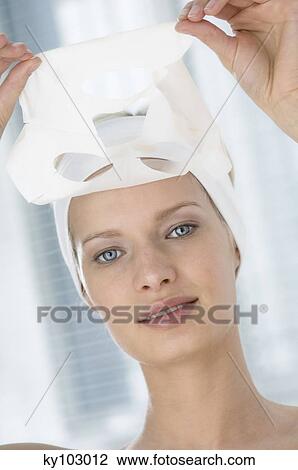 Portrait of a young woman taking off a beauty paper on her face (studio) View Large Photo Image Stock Image - Portrait of a young woman taking off a beauty paper on her face (studio). Fotosearch