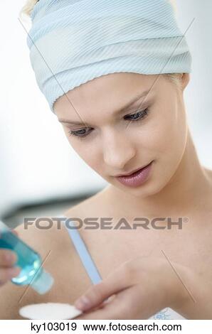 Young Woman face pouring on lotion in cleansing cotton, close-up (studio) View Large Photo Image Stock Photo - Young Woman face pouring on lotion in cleansing cotton, close-up (studio). Fotosearch