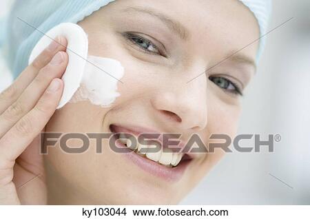 Young Woman face using a cleansing cotton on her cheek, close-up (studio) View Large Photo Image Picture - Young Woman face using a cleansing cotton on her cheek, close-up (studio). Fotosearch