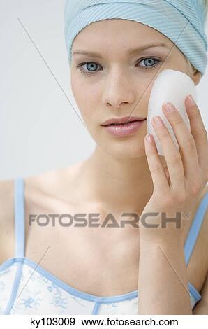 Young Woman face with make up, holding a bath sponge on her cheek (studio) View Large Photo Image Stock Photo - Young Woman face with make up, holding a bath sponge on her cheek (studio). Fotosearch