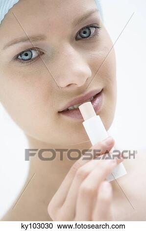 Young Woman face with make up, looking at the camera, using a lip balm, close-up (studio) View Large Photo Image Stock Image - Young Woman face with make up, looking at the camera, using a lip balm, close-up (studio). Fotosearch