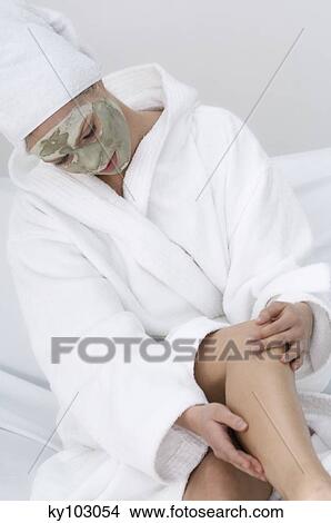 Young woman with beauty mask on her face, massaging her leg View Large Photo Image Picture - Young woman with beauty mask on her face, massaging her leg. Fotosearch