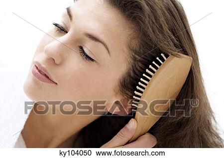 Stock Image - Portrait of a young woman brushing her hair. Fotosearch