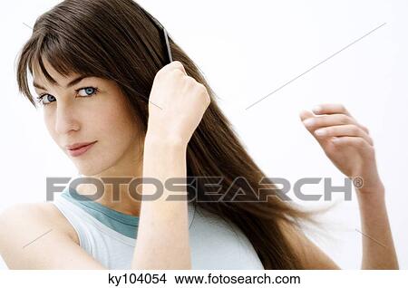 Portrait of a young woman combing her hair View Large Photo Image Picture - Portrait of a young woman combing her hair. Fotosearch