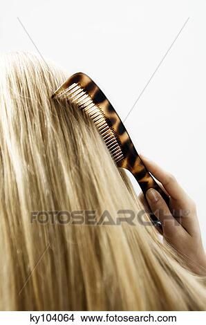 Portrait of a young woman combing her hair, view from the back, close up (studio) View Large Photo Image Picture - Portrait of a young woman combing her hair, view from the back, close up (studio). Fotosearch