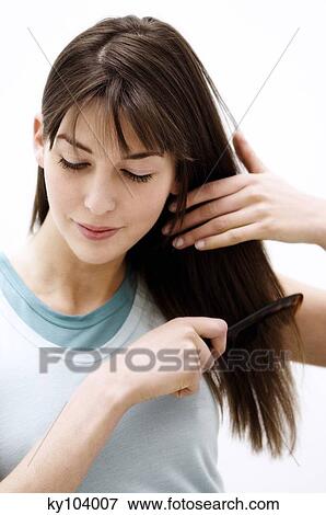 Portrait of a young woman combing her hair View Large Photo Image Stock Photo - Portrait of a young woman combing her hair. Fotosearch